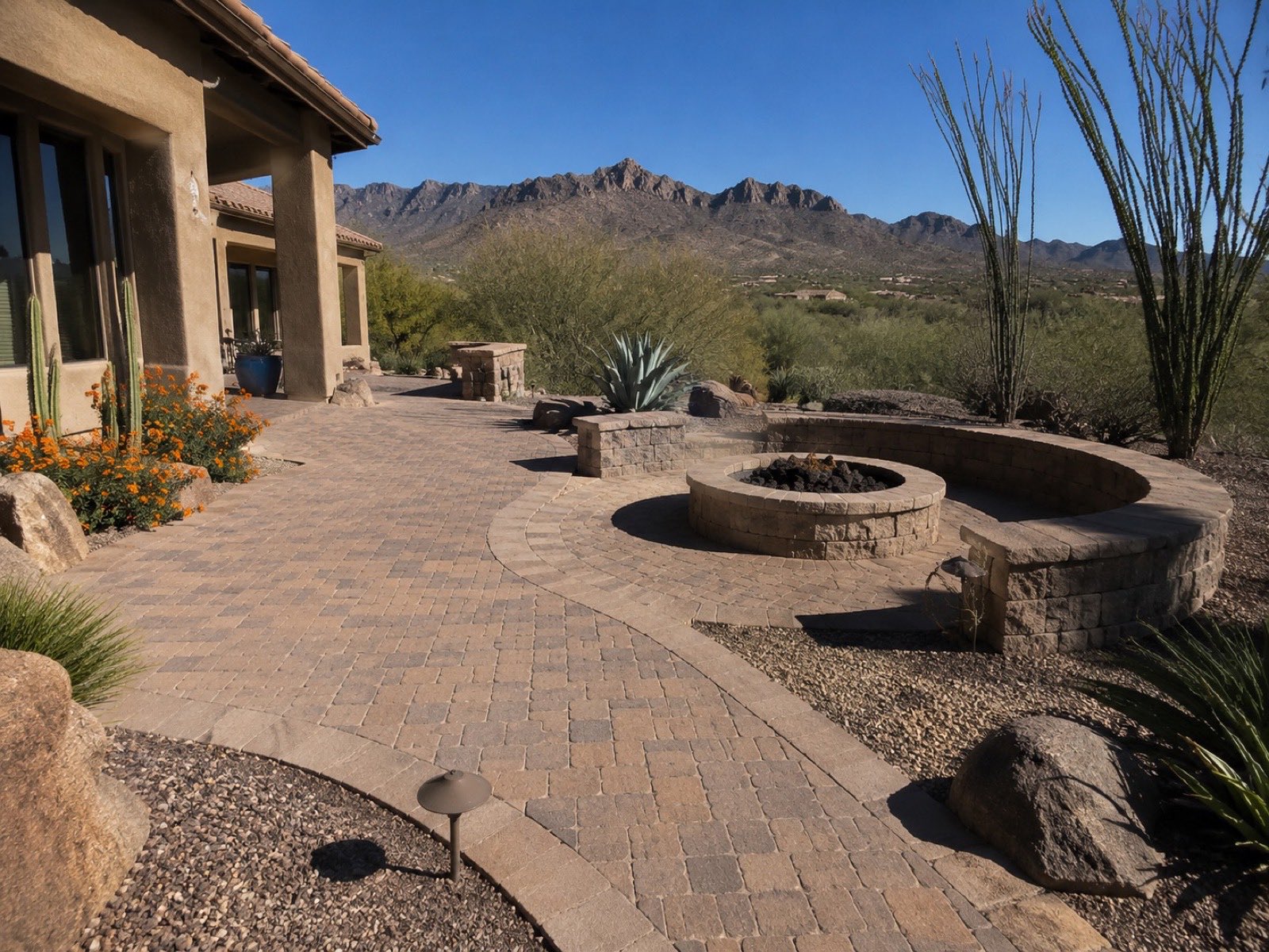 Paver patio with circular fire pit and curved seat wall framed by mountain views
